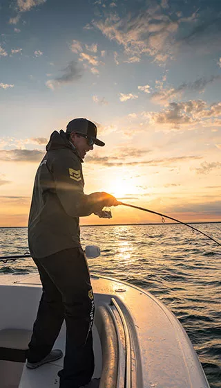 A man fishing on a boat with a trolling motor in the background